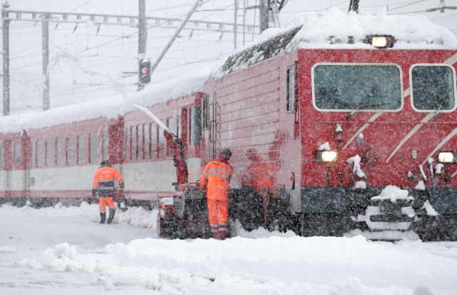 Radnici čiste šine na željezničkoj stanici u Disentis u Švajcarskoj. Јak sneg u jugoistočnoj Švajcarskoj izazvao je probleme u železničkom saobraćaju.