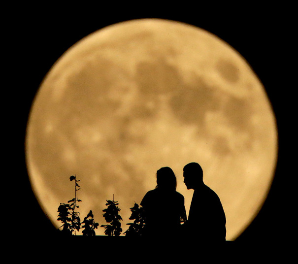 Par sjedi na obali rijeke Misuri i posmarta mjesec kako raste u blizini Kanzas Sitija.