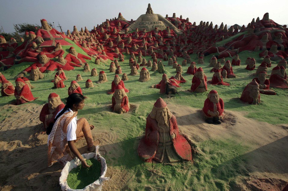 Učenik umjetnosti na pijesku Sudaršan Patnajk pravi Djeda mrazove na plaži u Puri, Indija. Skulpture su dio pokušaja da se obori Ginisov rekord.