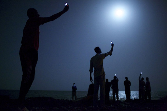 Afrički migranti u DŽibutiju stoje na mjesečini pokušavajući s telefonima da uhvate bolji signal... (Foto: John Stanmeyer)