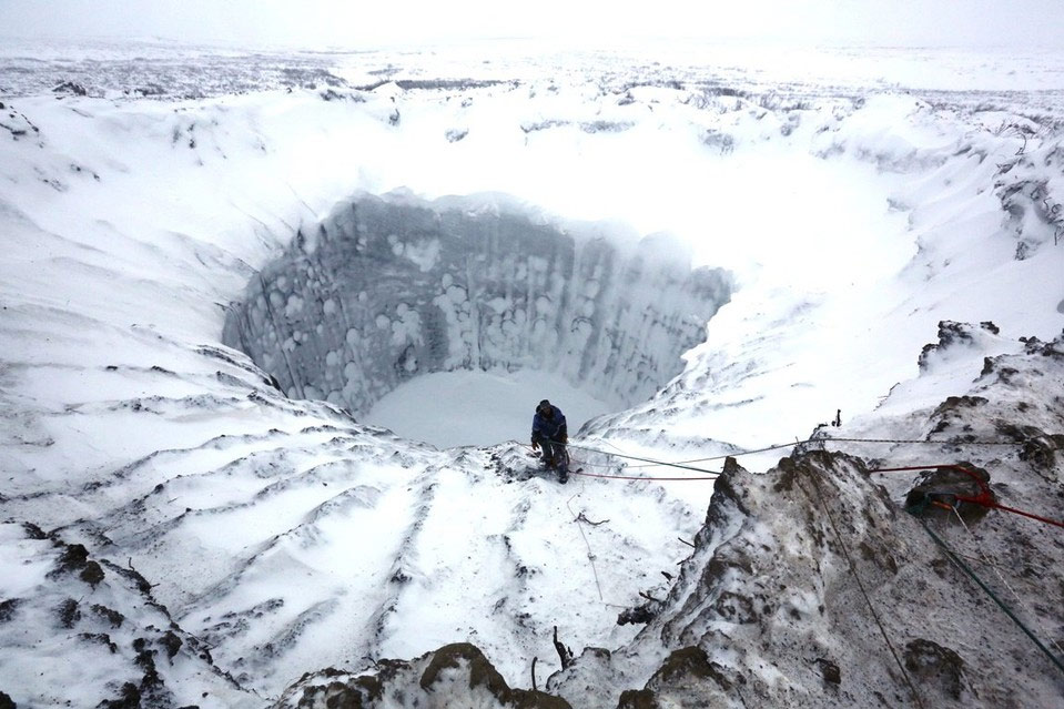 Ruski naučnik stoji na ivici misterioznog kratera nedavno otkrivenog u sjevernoj Rusiji. Јedna od teorija njegovog nastanka jeste da se zapalio gas zarobljen pod zemljom. (foto: Vladimir Pushkaryov/Russian Center for Arctic Exploration)